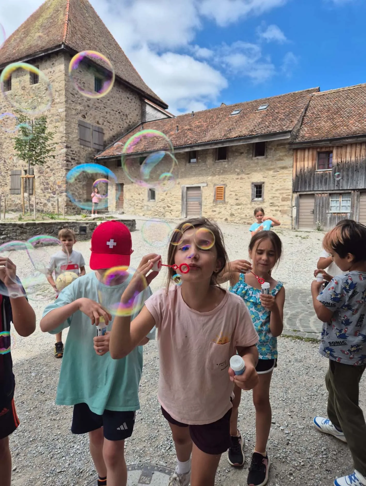 Enfants qui font des bulles de savon dans la cour d’une maison de camp